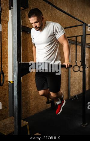 Sportlicher Mann, der Trizepsdips mit Körpergewicht und Schwerpunkt auf Krafttraining macht Stockfoto