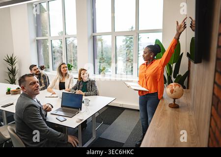 Eine vielfältige Gruppe von Personen, die an einem Tisch sitzen und in ihren Laptops vertieft sind. Sie scheinen an einem Projekt zu arbeiten oder an Aufgaben zu arbeiten, mit einer fokussierten und produktiven Atmosphäre. Stockfoto