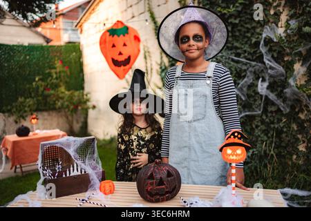 Zwei Kinder tragen Hexenkostüme während einer Halloween-Party im Garten Stockfoto