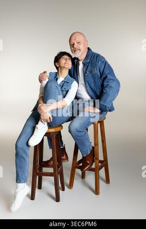 Ein liebevolles Seniorenpaar sitzt eng und nimmt fröhlich ihre goldenen Jahre zusammen an. Stockfoto