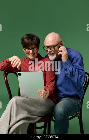Fröhliche Senioren lachen, während sie mit einem Tablet interagieren und ihre liebevolle Bindung unterstreichen. Stockfoto
