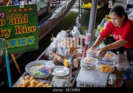 Frauen bereiten auf dem schwimmenden Markt Damnoen Saduak in Ratchaburi, Thailand, Mango-Kleberreis und thailändische Desserts zu Stockfoto