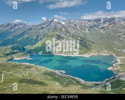 Blick aus der Vogelperspektive auf den Montespluga See mit türkisfarbenem Wasser, umgeben von alpinen Bergen und Damm in Valchiavenna, italienische Alpen, malerische Sommerlandschaft Stockfoto