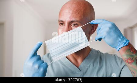 Gesundheitsarbeiter tragend chirurgische Maske und Handschuhe Setzen auf schützende Gesichtsmaske in Scrubs Stockfoto