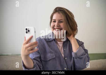 Frau in Übergröße, die Selfie mit Smartphone, Videoanrufe, soziale Medien, Online-Kommunikation, Fernfreundschaft, mobiler Lebensstil, positive Körperhaltung, Selbstvertrauen Stockfoto