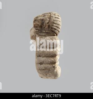 Fragment einer Figur. Kopf einer polychromen Figur, die ursprünglich wahrscheinlich eine Frau darstellte, die auf einem Bett lag und den Kopf auf einem Kissen auflegte. Der Kopf der Frau trägt eine kurze, gestreifte Perücke. Hinter dem Kopf ist die Hand einer Frau sichtbar, die wie der Kopf auf einem Gegenstand liegt, der ein Kissen oder Stoffbolzen darstellen kann. 332 v. Chr.–395 n. Chr.; ptolemäische Zeit–römische Zeit. Ägypten. Figur. Höhe 2,8 cm; Breite 5,6 cm; Tiefe 2,5 cm., Ein abgetragenes Steinfragment mit einer abgerundeten Oberseite und mehrschichtiger, gerippter Textur wird auf einem glatten grauen Hintergrund in Beige- und hellbraunen Tönen gezeigt Stockfoto