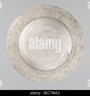 Teller, Habib Joo & Sons Handwerker, florale und geometrische Ornamente, Kronen, Medaillon gefüllt mit floralem Ornament mit einer ineinander verwobenen Krone und der Nummer: XXXI., 1868, Indien, Srinagar, Gefäß, Höhe 2,5 cm, Breite 28,8 cm, Gewicht 440 g, Eine runde, flache Metallschale mit verziertem, sich wiederholendem, geschnitztem Muster, einem glatten zentralen Well mit einem leicht eingeschnittenen kreisförmigen Motiv und einer silbrig-grauen Oberfläche mit subtilen Schimmer und leichten, dunkleren Patina. Stockfoto