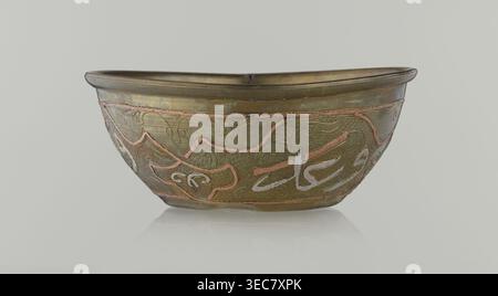 Schüssel, islamische Kunst, arabische Kultur, arabische Ornamente, Kalligraphie, arabische Inschriften, geometrische Motive, 19. Jahrhundert, Naher Osten, möglicherweise Syrien, Gefäß; Höhe 4,9 cm, Durchmesser 13,3 cm, Eine flache Metallschale mit abgerundetem Rand sitzt vor einem hellgrauen Hintergrund und zeigt eine metallische Oberfläche in gedämpften Gold- und Messingtönen mit dunkleren Patinatönen. Das Äußere der Schüssel ist mit erhöhten gewundenen Mustern in kupferrosa Tönen und helleren Intarsien in einem cremefarbenen Farbton verziert, die vor einem strukturierten Hintergrund mit kleinen, genoppten Einkerbungen stehen. Die Rand- und Basiskanten erscheinen leicht Stockfoto