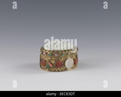 Box mit Deckel, Chinesisch, Qing-Dynastie Ende des 19. Jahrhunderts. Höhe 5,0 cm, Breite 6,6 cm, Tiefe 8,2 cm, Gewicht 0,17 kg. Der Deckel ist mit einer Jadeite-Plakette eingelegt, auf der ein Flachreliefbild eines Löwen abgebildet ist, der mit einem Ball spielt. Die äußere Wand zeigt Motive von Schmetterlingen, Fledermäusen und das Shou-Symbol für Langlebigkeit aus Halbedelsteinen in den Kulissen. Hintergrund: Pflanzenzweig mit filigraner Struktur. Gefäß/Behälter., Eine kleine ovale dekorative Box sitzt auf einer glatten Oberfläche vor einem abgestuften grauen Hintergrund, mit einem gewölbten hellgrünen Deckel mit erhöhten Motiven und einem Körper aus kunstvollen Goldmetallwerken, die mit einem verziert sind Stockfoto
