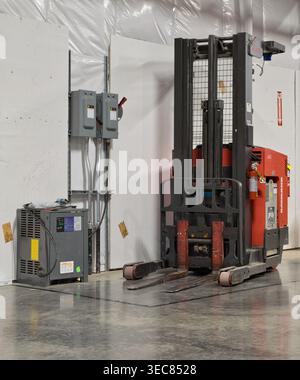 Houston, Texas USA 27. April 2026: Schubmaststapler und Batterieladestation im Lager abgestellt. Stockfoto
