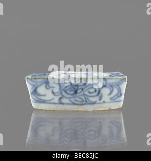 Schiff, Wiederbesitz Krakau, Keramik, chinesische Kunst, chinesische Kultur, Pflanzenschmuck, blau-weißes Porzellan, ziegelrote Kugeln aus Ton gebrannt, Anfang des 20. Jahrhunderts, China, Gefäß, Höhe 2,6 cm, Breite 7,4 cm, Tiefe 4,7 cm, Ein kleines rechteckiges keramisches Objekt, das zentriert auf einem glatten grauen Hintergrund sitzt und eine weiße Grundfarbe mit handgemalten, fließenden blauen Wirbelmustern entlang der sichtbaren Seiten und oberen Kanten zeigt; die Keramik hat einen leicht unebenen Rand mit subtilen bräunlichen Flecken und einigen Verfärbungen, und sie liegt auf einer reflektierenden Oberfläche auf, die ein gedämpftes Spiegelbild des blau- Stockfoto