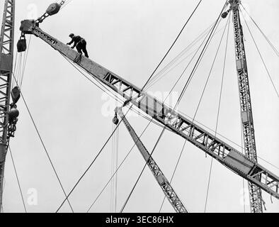 Dieses berühmte Foto aus den 1930er Jahren von Lewis W. Hine zeigt einen Bauarbeiter, der einen Derrick hoch über New York City klettert, wahrscheinlich während des Baus des Empire State Building. Das Bild, das Teil von Hines Dokumentation von „Männer bei der Arbeit“ ist, unterstreicht den Mut und das Können der Arbeiter, die am Bau großer städtischer Infrastrukturen beteiligt sind. Stockfoto
