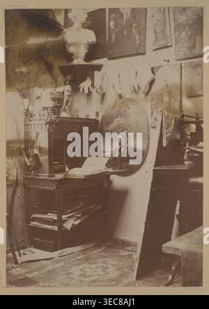 Ignacy Jasiński Malstudio 1833–1878 im Hotel Europejski in Warschau; Ignacy Jasiński 1833–1878, Fotografie, Druck auf der ganzen Fläche auf der Rückseite der 22. Seite eines Albums, 1869–1878; Thema: Innenräume, Künstleratelier, Maler; Medium: Fotografie Natur Fotografie/Fotografie in einem Album; Abmessungen: Höhe 10,3 cm, Breite 7,3 cm; polnische Gemälde Reproduktion/Ikonographie., Eine übersichtliche Innenaufnahme mit einem Holztisch oder Schrank mit Büchern und Papieren, eine runde bemalte Platte, die an die Wand gelehnt ist und eine sitzende Figur darstellt, eine Büste auf einem Sockel in der Nähe des Stockfoto