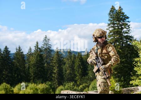 Bewaffneter Soldat in Multicam Camouflage in Forest Mountain Landscape Stockfoto