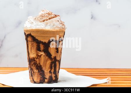 Gekühltes Schokoladenkaffee serviert mit Schlagsahne in einem klaren Plastikbecher. Stockfoto