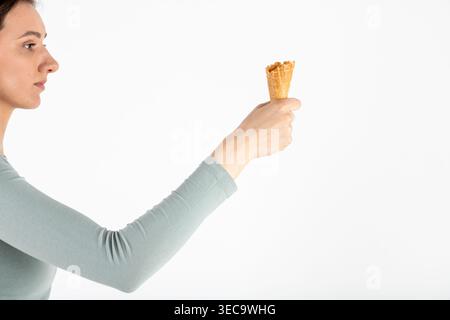 Eine Frau, die eine leere Waffeleiskegel auf weißem Hintergrund hält Stockfoto