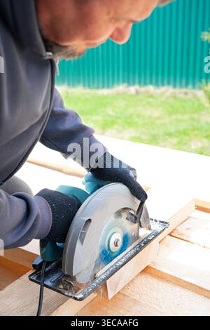 Zimmermann mit Kreissäge Holz schneiden, Arbeitsgang schließen. Rahmenhausbau, Heimwerkerkonzept aus ökologischem Holz. Facharbeiter schneiden Stockfoto