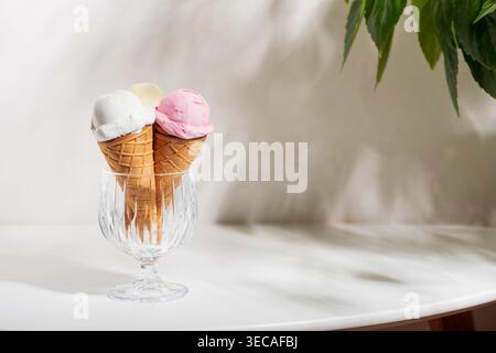 Frische Gourmet-Komposition mit drei Eiskegeln in einer klaren Glasschale, mit Aromen von Vanille, Erdbeere und Zitrone auf weißem Hintergrund Stockfoto