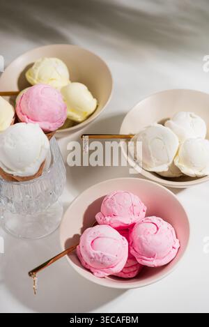 Helle Gourmet-Komposition mit drei Schüsseln Eis in verschiedenen Geschmacksrichtungen: Erdbeere mit frischem Obst, Vanille oder Kokos mit Minzblättern, Stockfoto