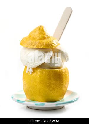 Kreative Dessertpräsentation mit cremigem Zitroneneis, serviert in einer frischen ausgehöhlten Zitronenschale mit Deckel und Löffel, isoliert auf weißem Hintergrund. Re Stockfoto