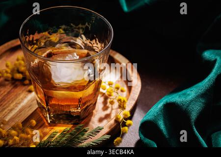 Whiskey Glass mit Top View und Eis- und Mimosa-Blumen im Frühling Stockfoto