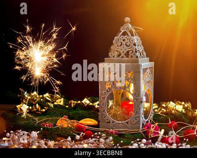 Weihnachtsdekoration mit leuchtendem Glitzer, Kerzen, einer Laterne, Tannenzweigen, Kegeln und getrockneten Orangenscheiben, Komposition Stockfoto