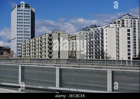 Stadtblick auf Wohngebäude und Hochhaus in Helsinki, Finnland, von einer Brücke mit Glasgeländern unter klarem blauem Himmel aus gesehen Stockfoto