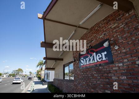 Buena Park, Kalifornien, USA - 11. April 2026: Nachmittagsverkehr passiert ein Restaurant Sizzler auf der Orangthrope Ave. Stockfoto