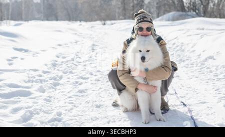 Porträt einer kaukasischen Frau, die ihren Hund bei einem Winterspaziergang umarmt. Stockfoto