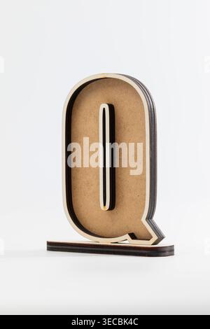 Der Holzbuchstabe Q steht hoch und kräftig. Das einfache, saubere Design unterstreicht die natürliche Struktur der Körnung. Dezenter Schatten verleiht minimalistischen Hintergründen Tiefe. Modern Stockfoto