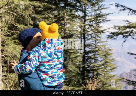 Eltern, die das Kind in einer Winterjacke halten, genießen den Blick auf den himalaya-Berg vom Aussichtspunkt aus Stockfoto