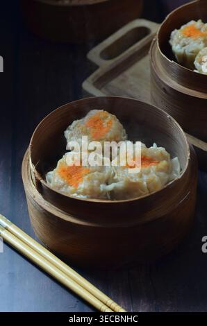 Siu Mai, eine Garnelendimsum, die in Bambusholzkorb gedampft wird. Stockfoto