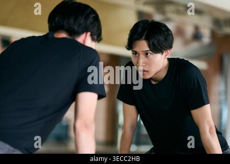 Zielgerichteter junger Japaner, der sein Formular in einem Fitnessspiegel überprüft Stockfoto