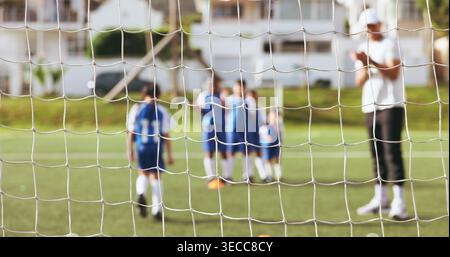 Netz, Fußball und Trainer mit Kindern für Elfmeterschießen, Fußballprozedur oder Sporttag auf dem Grasfeld. Menschen, Kinder oder Team mit anfeuerndem Lehrer Stockfoto