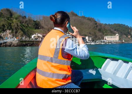 Hafenarbeiter mit Sicherheitsweste telefonieren auf dem Mobiltelefon Stockfoto