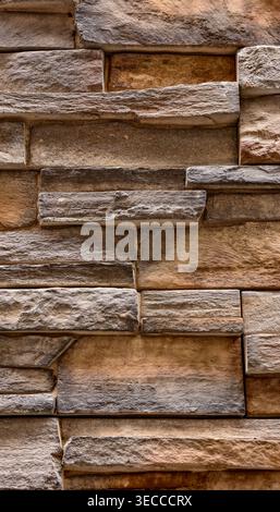 Wandstruktur aus Naturstein mit mehrschichtigem grauem, braunem und beigefarbenem Mauerwerk, rauer Oberfläche und organischen Variationen. Hochauflösender 8K-Hintergrund Stockfoto