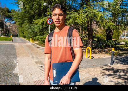 Junge Studentin, die auf dem Universitätscampus eine Akte hält Stockfoto