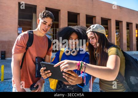 Gruppe verschiedener Studenten, die ein Tablet auf dem Campus verwenden Stockfoto