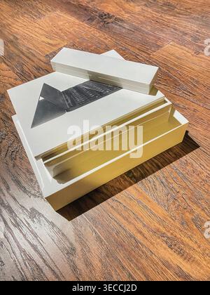 Minimalistischer Aufbau von gestapelten Technologiepaketen auf einer Holzoberfläche. Klares Design, warme Beleuchtung und moderne Ästhetik schaffen ein Konzept Stockfoto