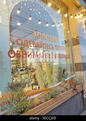 Woronesch, Russland - 7. September 2021: Gemütliches Café-Fenster mit warmen Lichterketten und saisonalen Dekorationen, mit einem russischen Zitat über kaltes Wetter Stockfoto
