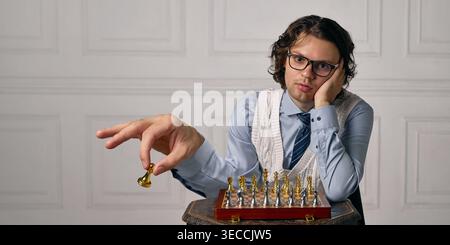 Schachspieler mit übergroßer Hand bewegt goldenes Stück über Bord in sauberem Innenraum. Stockfoto
