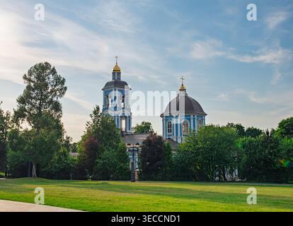 Orthodoxe Kirche mit blauer Kuppel und Glockenturm, die an einem hellen Tag in einem Moskauer Park hoch steht Stockfoto