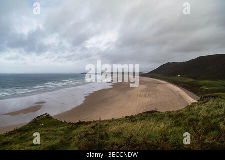 Panoramablick auf den weiten Sandstrand in Rhossili Bay und Llangennith unter einem stimmungsvollen Himmel, Gower Peninsula, Südwales Stockfoto