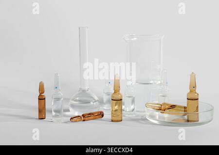 Medizinische Ampullen mit Laborglas und Petrischale auf grauem Hintergrund Stockfoto