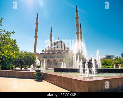 Grosny, Russland - 30. Juli 2021: Akhmad-Kadyrow-Moschee mit großen Minaretten und zentraler Kuppel, die sich in einem hellen Brunnen unter klarem Himmel spiegelt Stockfoto
