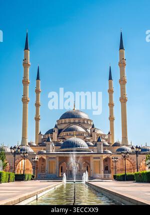 Grosny, Russland - 30. Juli 2021: Die majestätische Achmad-Kadyrow-Moschee und ihr reflektierendes Becken unter einem klaren blauen Himmel Stockfoto