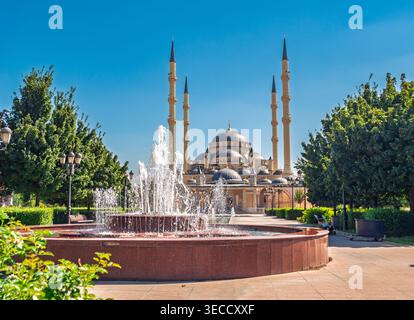 Grosny, Russland - 30. Juli 2021: Majestätische große Moschee von Grosny mit erfrischendem Wasserbrunnen im Vordergrund an einem klaren Sommertag Stockfoto
