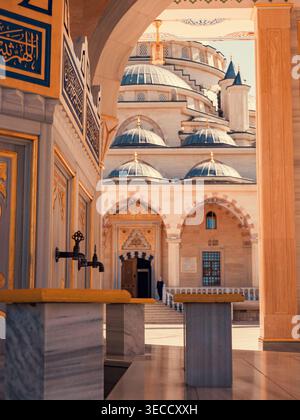 Grosny, Russland - 30. Juli 2021: Das Herz der Tschetschenischen Moschee durch einen bogenförmigen Eingang, der große Kuppeln und Marmorwaschanlagen enthüllt Stockfoto