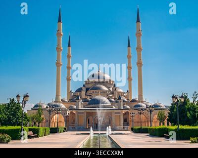 Grosny, Russland - 30. Juli 2021: Die majestätische Achmad-Kadyrow-Moschee und ihr reflektierendes Becken unter einem klaren blauen Himmel Stockfoto