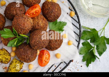 Stehen Sie mit köstlichen Falafelbällchen, Kichererbsen und Tomaten auf hellem Hintergrund, Nahaufnahme Stockfoto